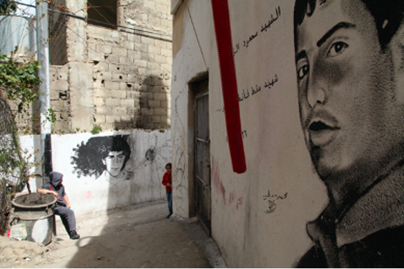 1. Murals by Mohammad Ma’ali portray two martyrs from Dheisheh: in the foreground, Mahmoud Zaghari, killed  in 2004 at the age of 22 during a clash with Israeli troops in Bethlehem, and in the background Nasser Alqasass, 15, killed in 1989 after stepping outside his home during a curfew. Photograph © 2016 Margaret Olin.